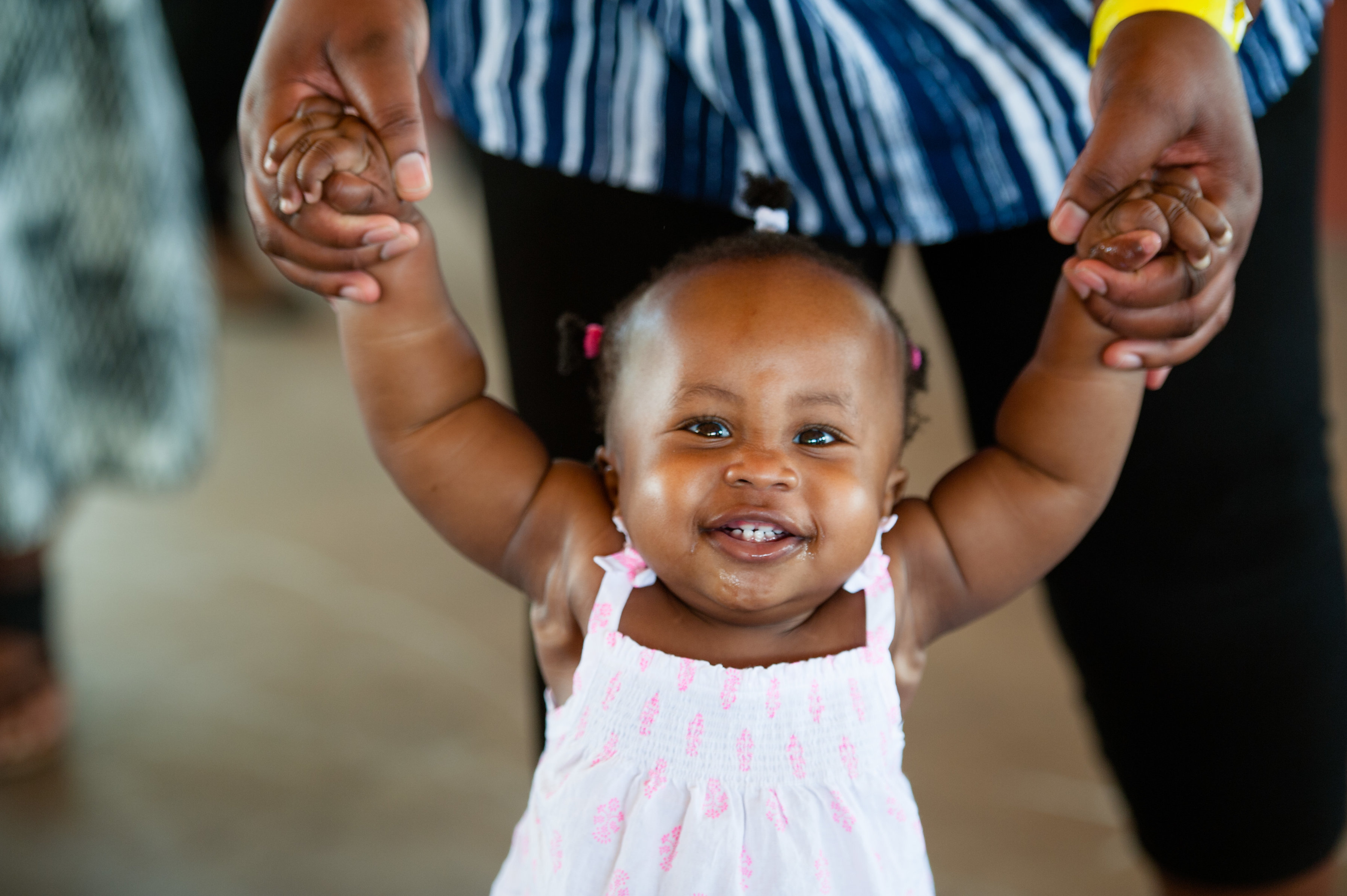 Child walking with arms held by parent