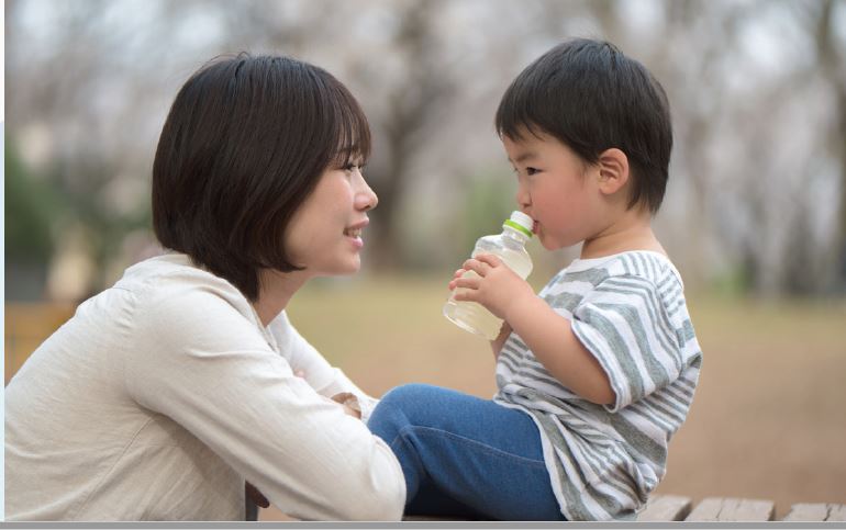 mother and child looking at each other, child drinking water