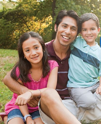 Dad hugging a girl and a boy in the park