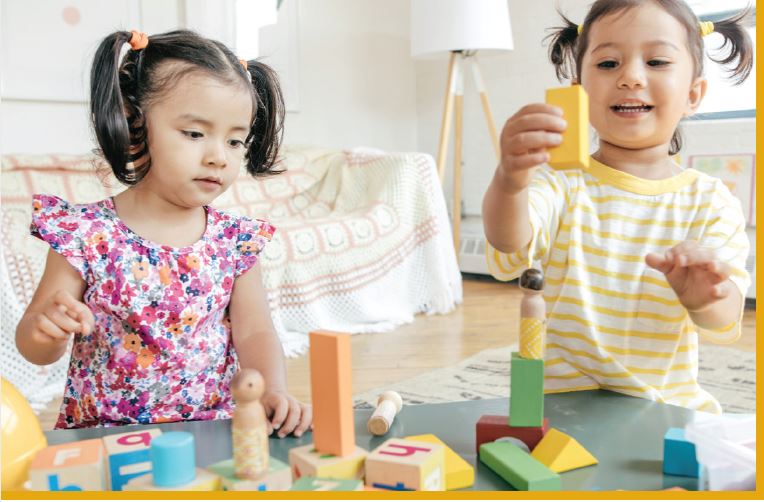 two girls playing together with color shape blocks 