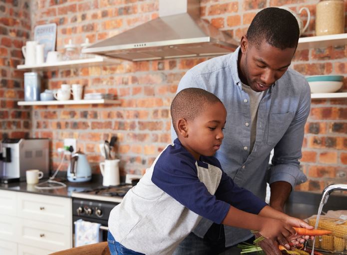 man and young boy washing carrots 