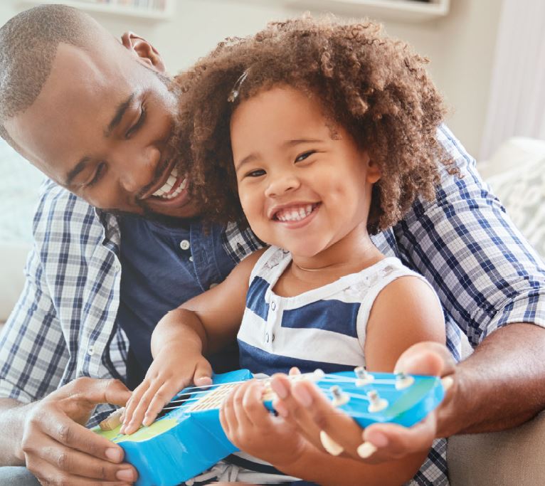 parent and child laughing and playing the guitar together