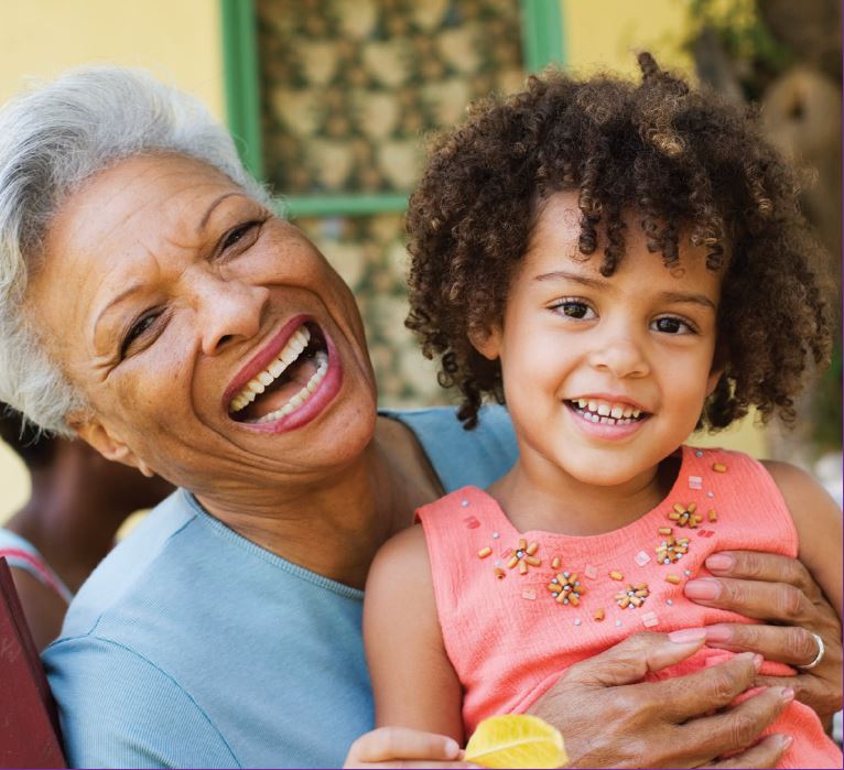 Elderly lady  laughing and hugging a little girl 