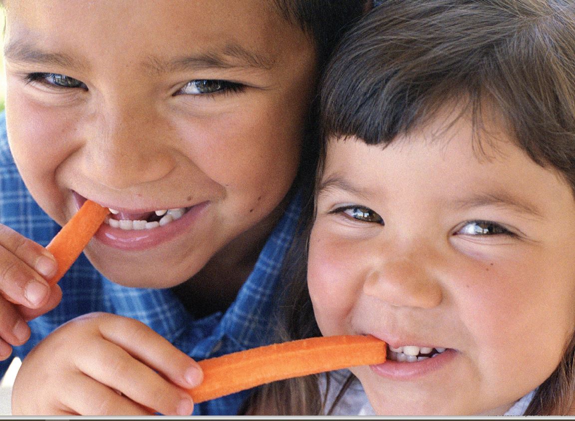 two young boys eating carrots 