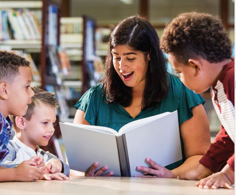 Female Librarian is reading  a book to  the children