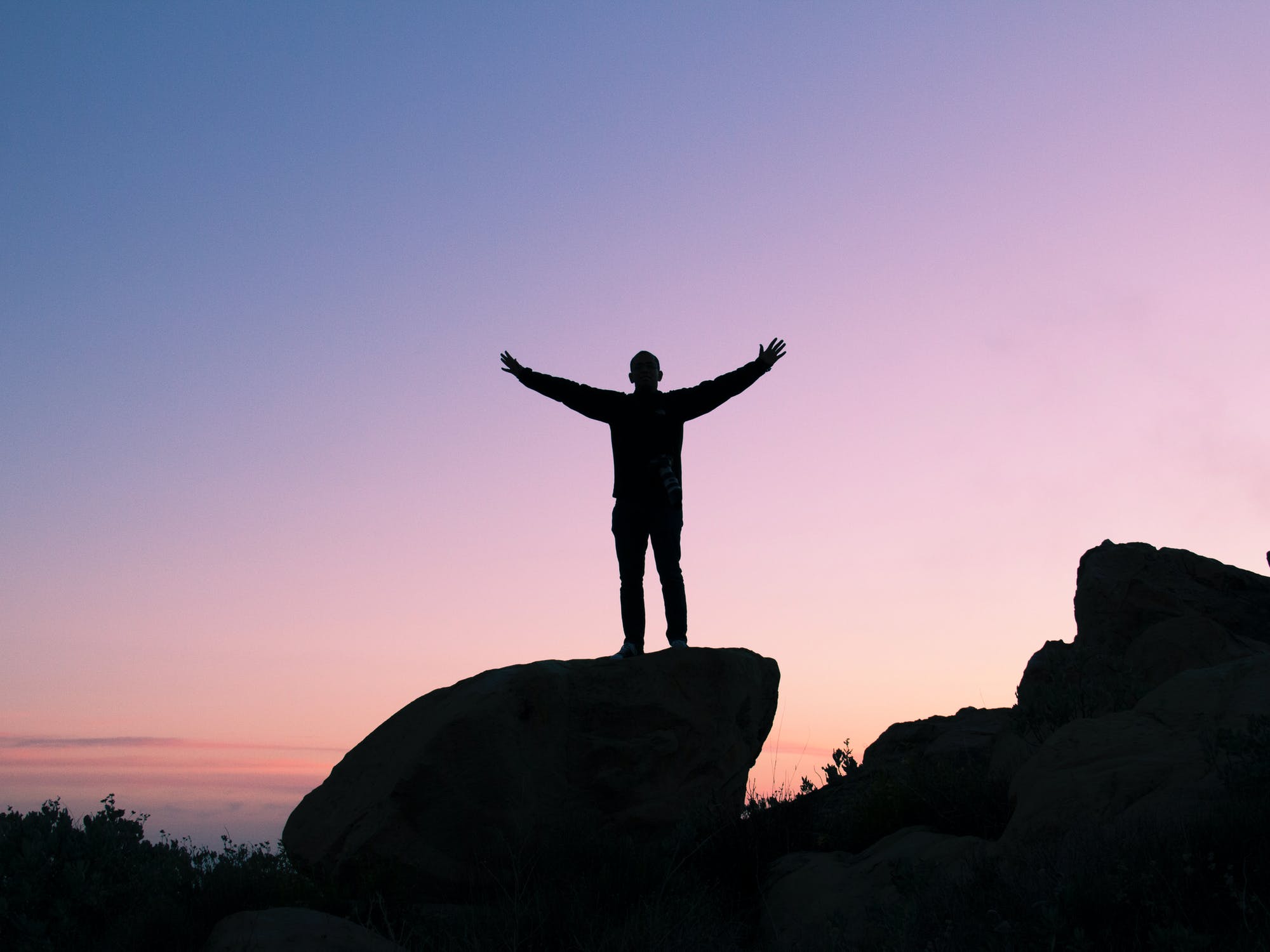 Man on rock with sunset in background