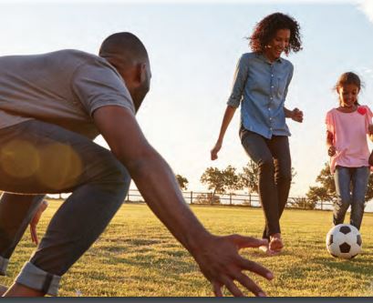 Father and mother playing soccer with their daughter 