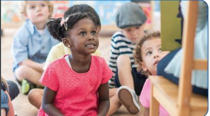 boys and girls sitting listening to a person reading