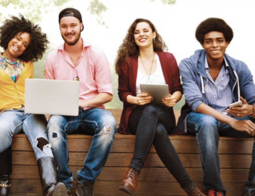 two males and two females smiling sharing a laptop